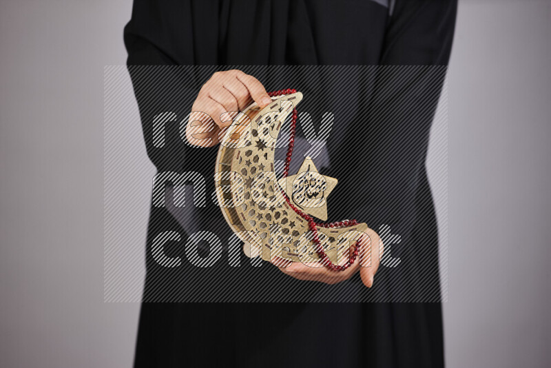 A woman in black abaya holding different ramadan lanterns in different positions