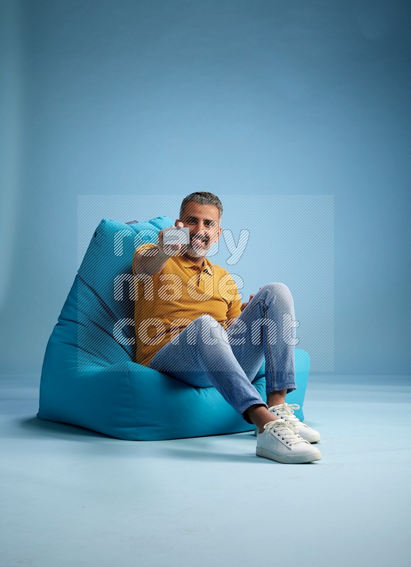 A man sitting on a blue beanbag and holding ATM card