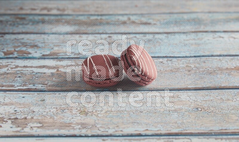 45º Shot of two Red Poppy Flower macarons on light blue wooden background