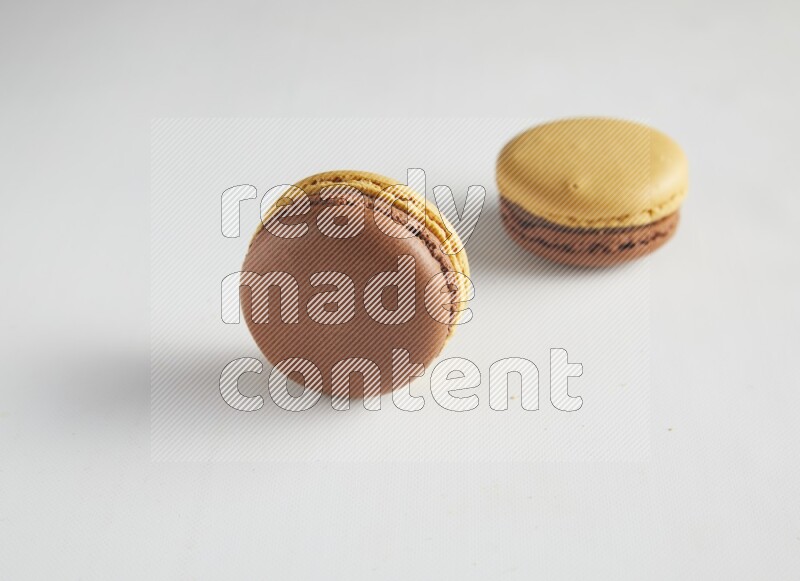 45º Shot of two Yellow and Brown Chai Latte macarons on white background