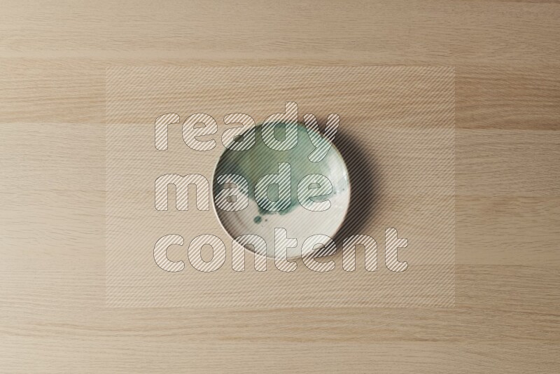 A multicolored pottery plate on light wooden background