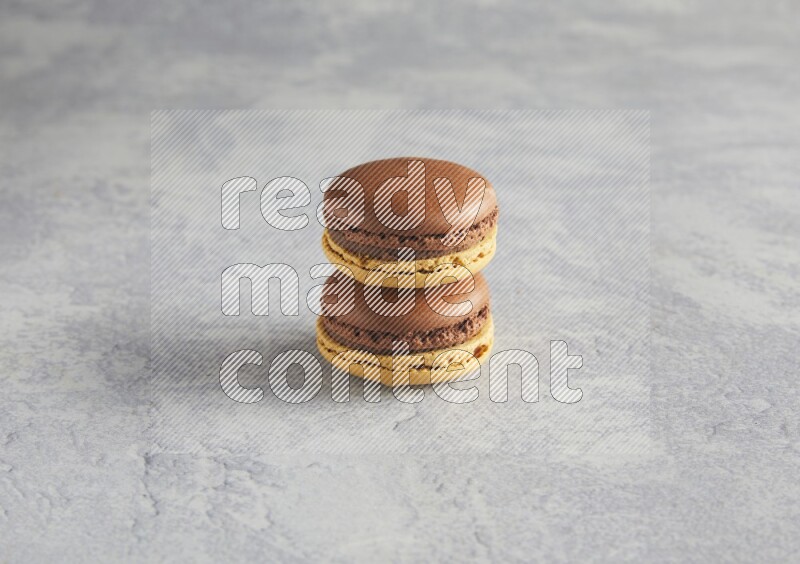 45º Shot of two Yellow and Brown Chai Latte macarons r on white  marble background