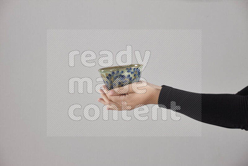 A woman in black abaya holding different pottery essentials in different positions