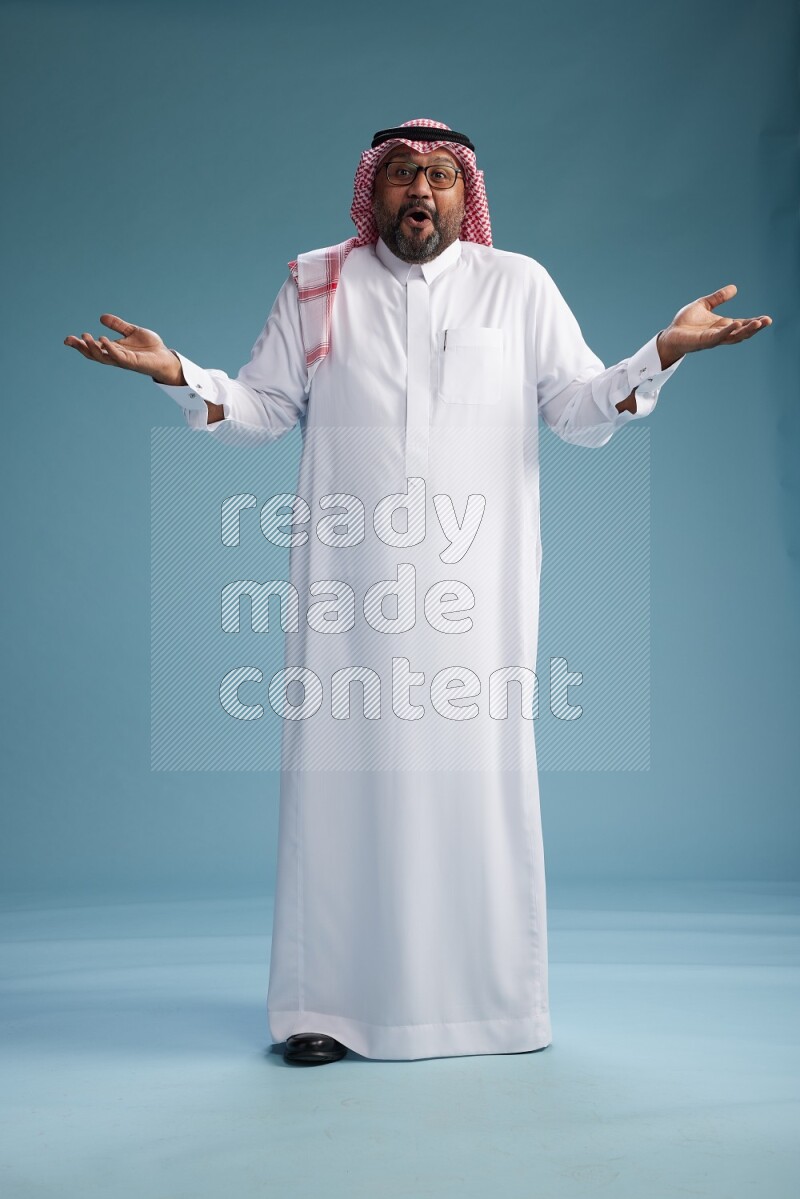 Saudi Man with shimag Standing Interacting with the camera on blue background