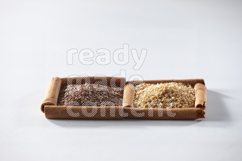2 squares of cinnamon sticks full of flaxseeds and sesame on white flooring