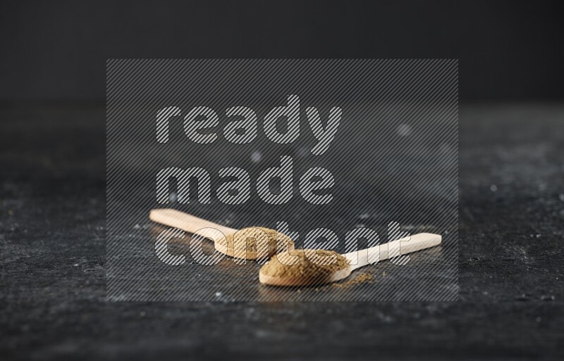 ملعقتان خشبيتان ممتلئتان ببودرة الكمون على خلفية سوداء