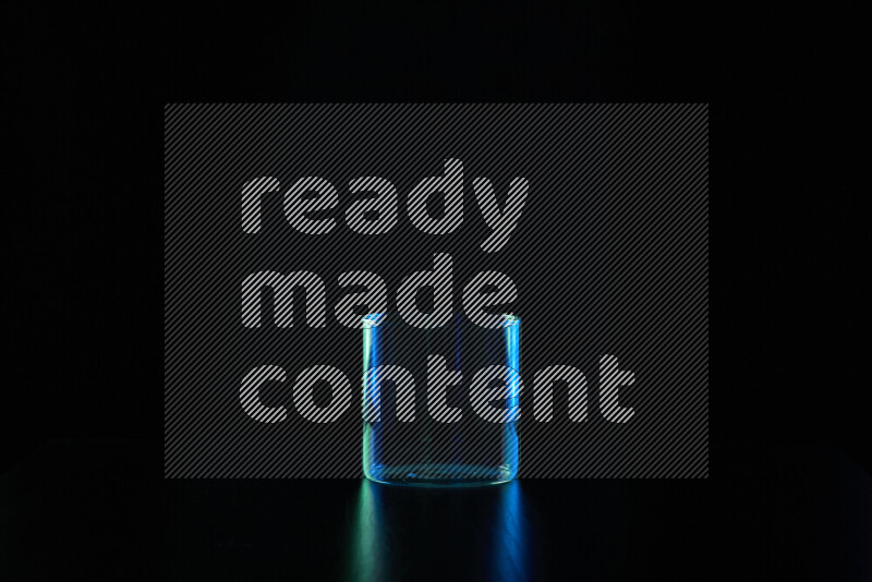 Glassware with rim light in blue and green against black background