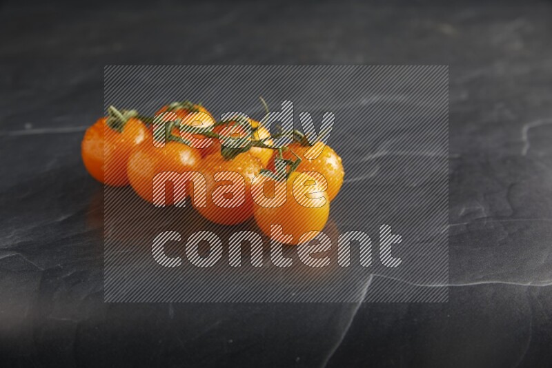 Orange cherry tomato vein on a textured black slate background 45 degree