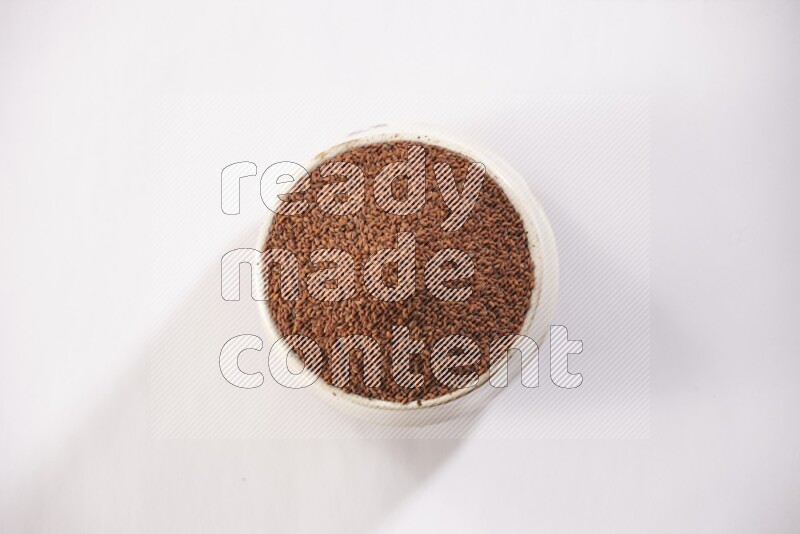 وعاء فخاري بيج ممتلئ ببذور حب الرشاد على خلفية بيضاء