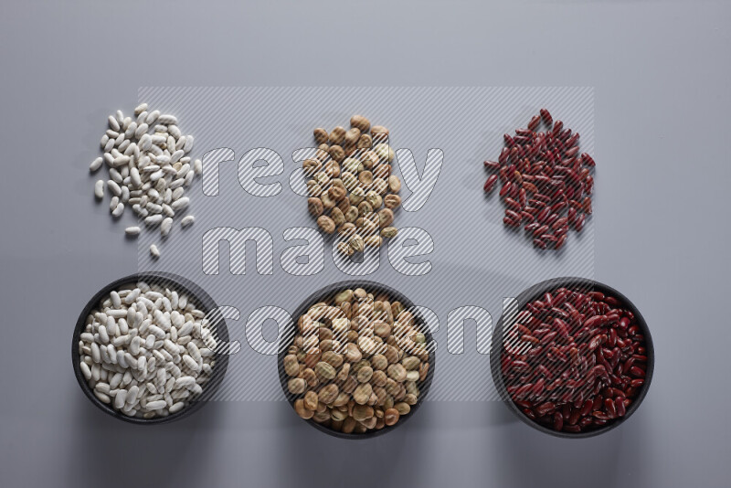 Legumes in pottery bowls on light grey background