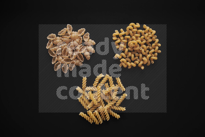 Different pasta types in bunches on black background