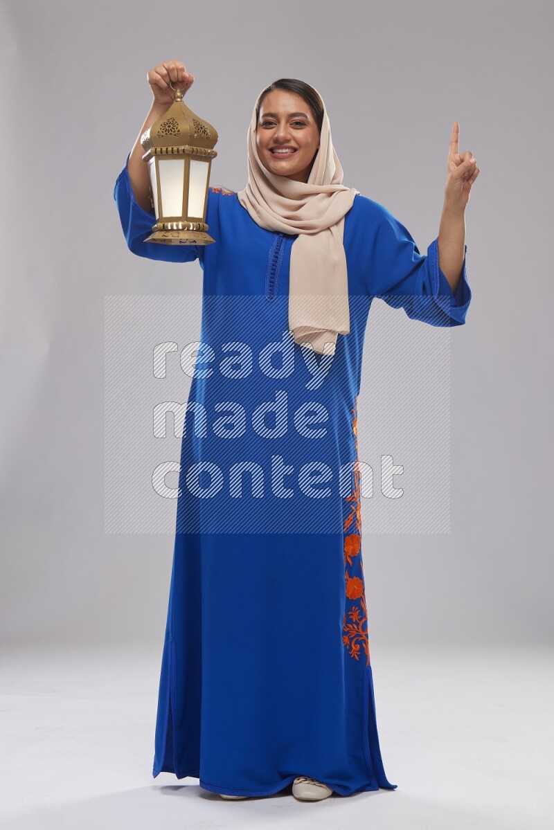 A Saudi woman standing wearing Jalabeya holding a lantern
