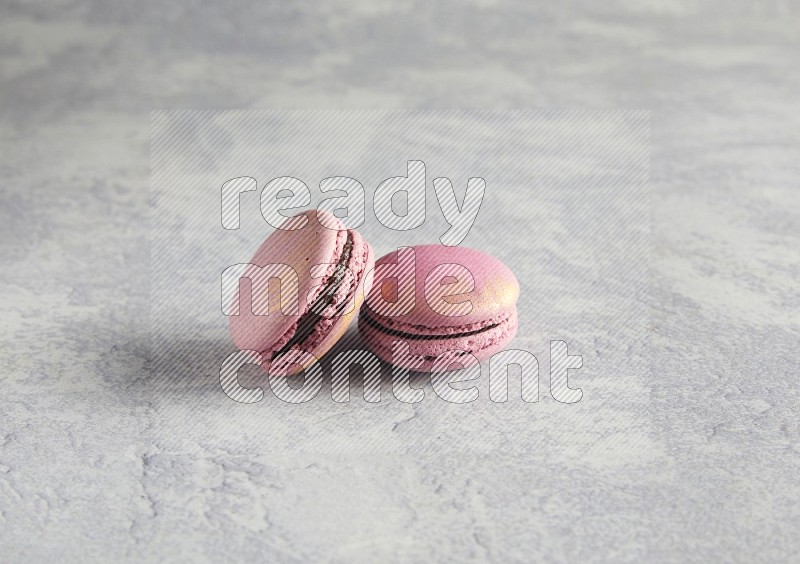 45º Shot of two Purple Strawberry macarons on white  marble background