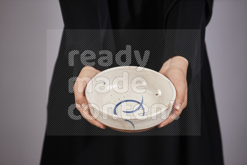 A woman in black abaya holding different pottery essentials in different positions