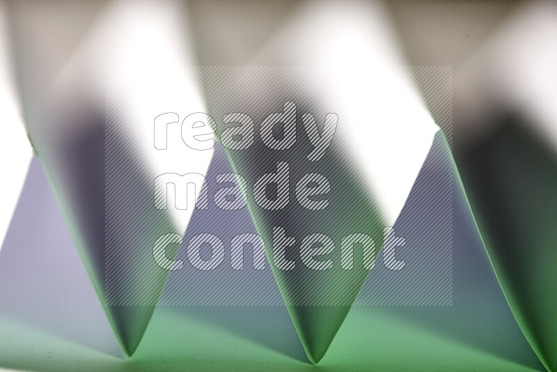 A close-up abstract image showing sharp geometric paper folds in white and green gradients