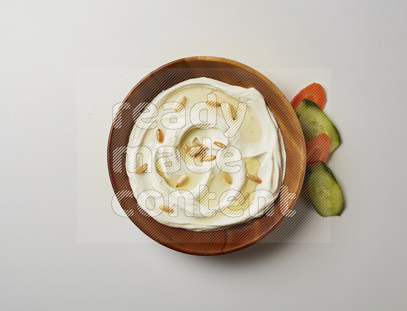 Lebnah garnished with pine nuts in a wooden plate on a white background