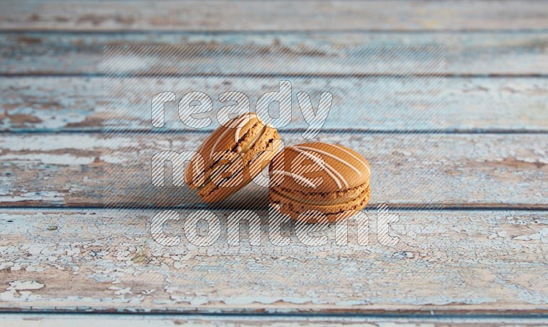 45º Shot of two Brown Irish Cream macarons on a  light blue wooden background