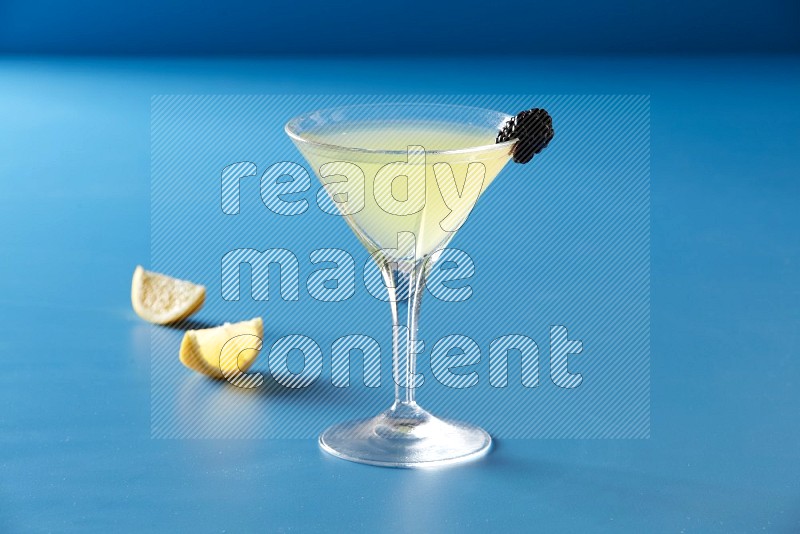 glass of lemon juice with berry on blue background