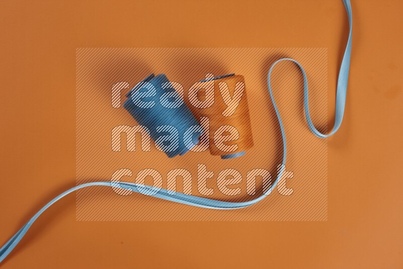 مجموعة من أدوات الخياطة والتفصيل زرقاء اللون على خلفية برتقالية