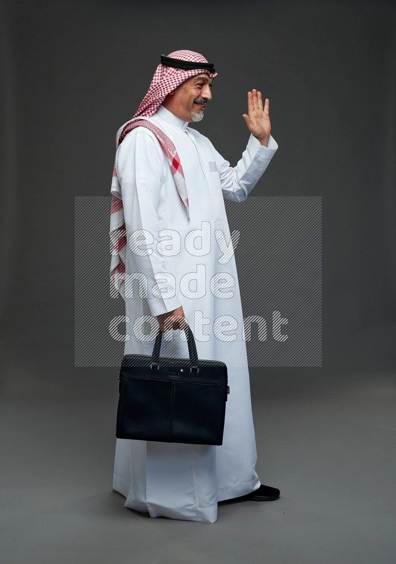 Saudi man with shomag Standing holding bag on gray background