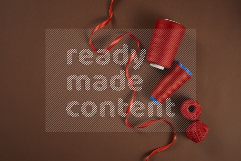 مجموعة من أدوات الخياطة والتفصيل حمراء اللون على خلفية بنية