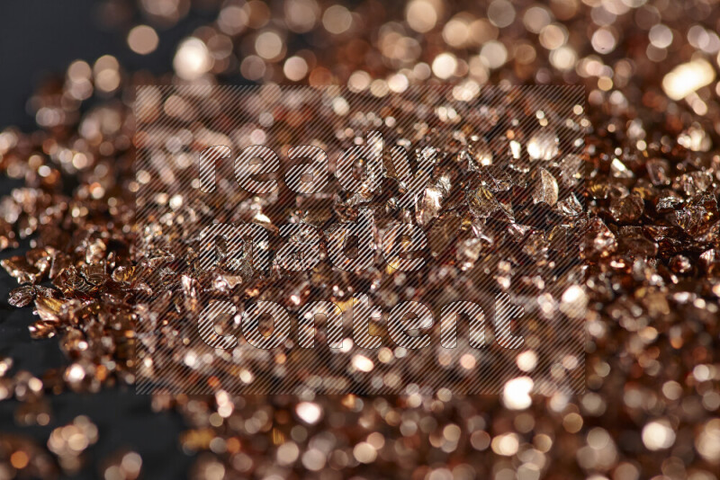 Bronze shimmering fragments of glass scattered on a black background