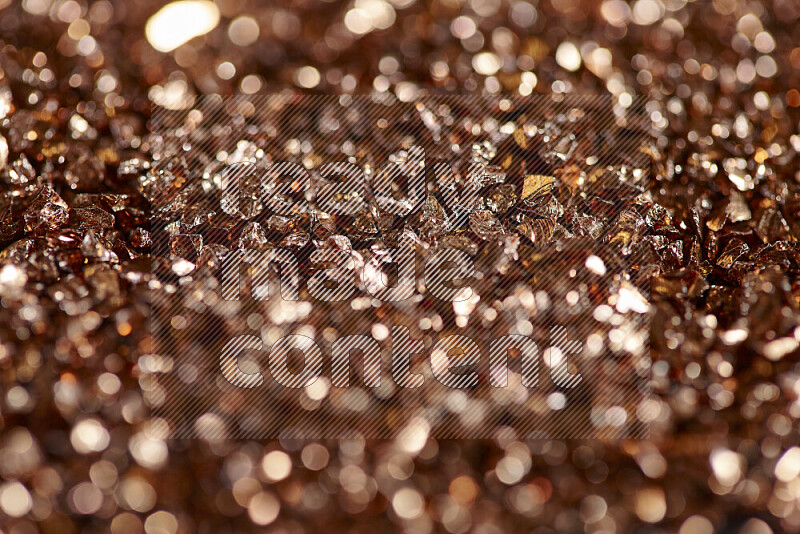 Bronze shimmering fragments of glass scattered on a black background