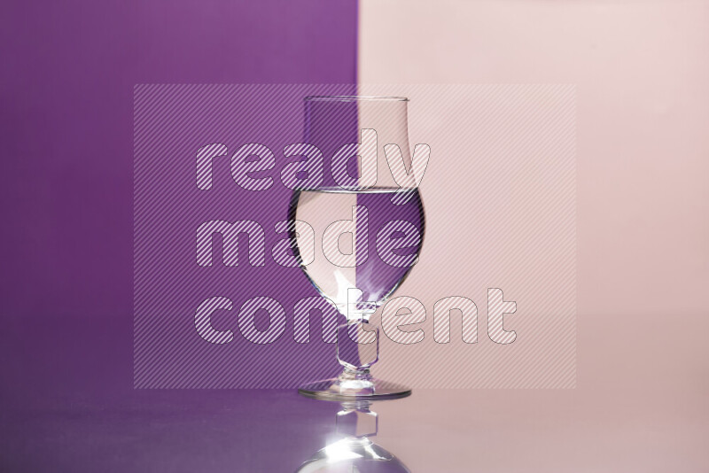 The image features a clear glassware filled with water, set against purple and rose background