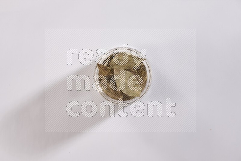 وعاء زجاجي ممتلئ بأوراق الغارعلي خلفية بيضاء