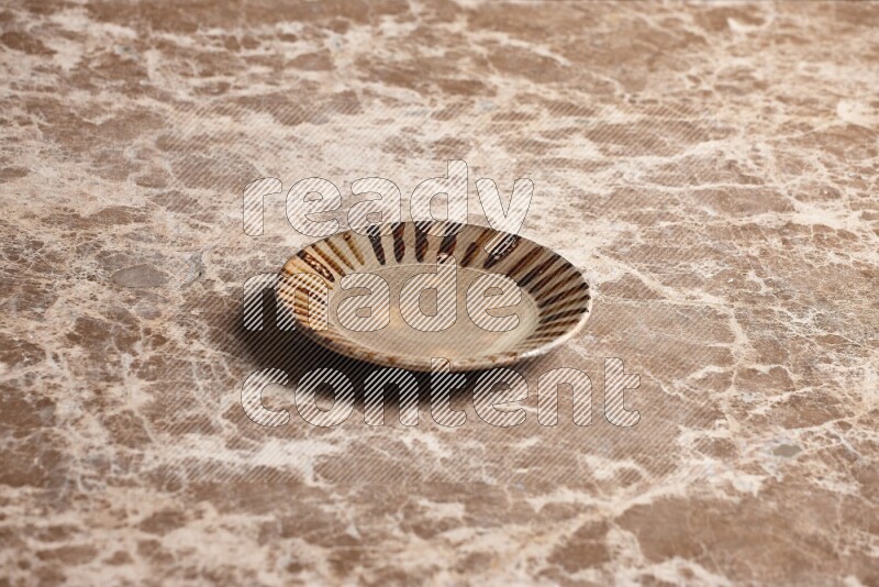 A multicolored pottery plate on beige marble background