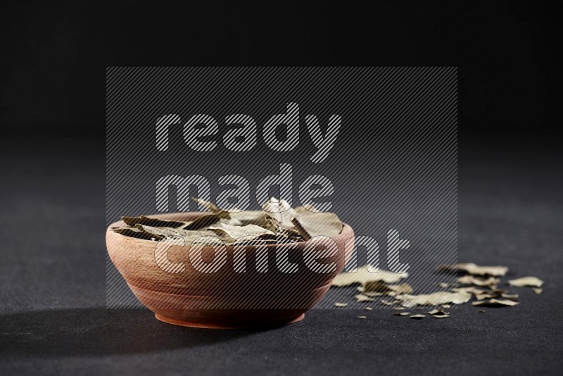 A wooden bowl filled with laurel bay on black flooring in different angles