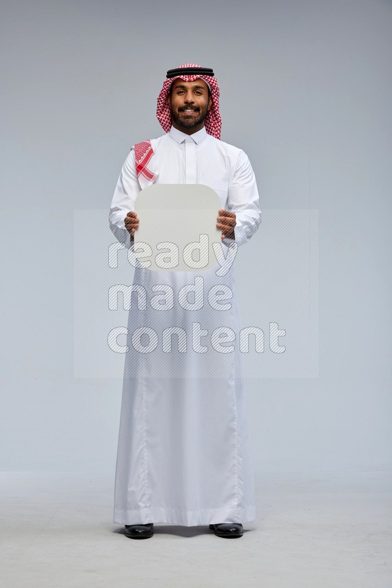 Saudi man Wearing Thob and shomag standing holding social media sign on Gray background