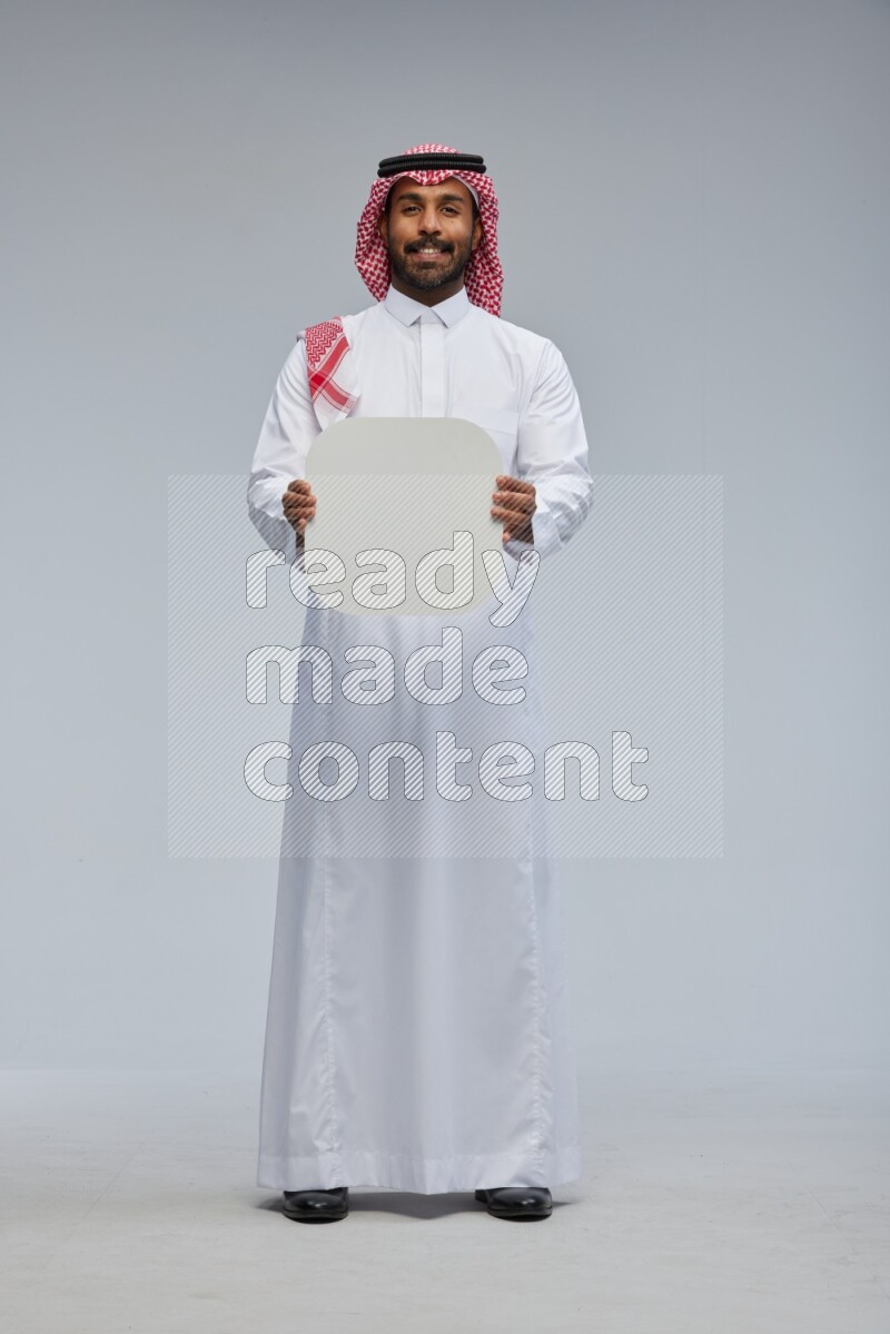 Saudi man Wearing Thob and shomag standing holding social media sign on Gray background