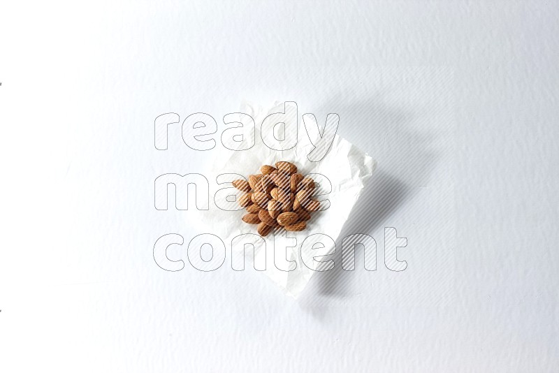 Peeled almonds on a crumpled piece of paper on a white background in different angles