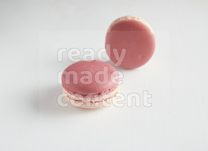 45º Shot of two Pink Litchi Raspberry macarons on white background