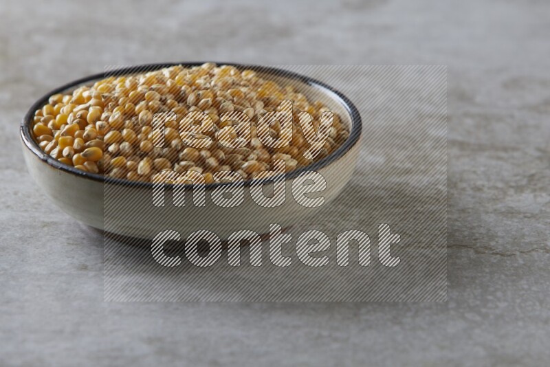 corn kernel in a multi-colored pottery bowl on a grey textured countertop