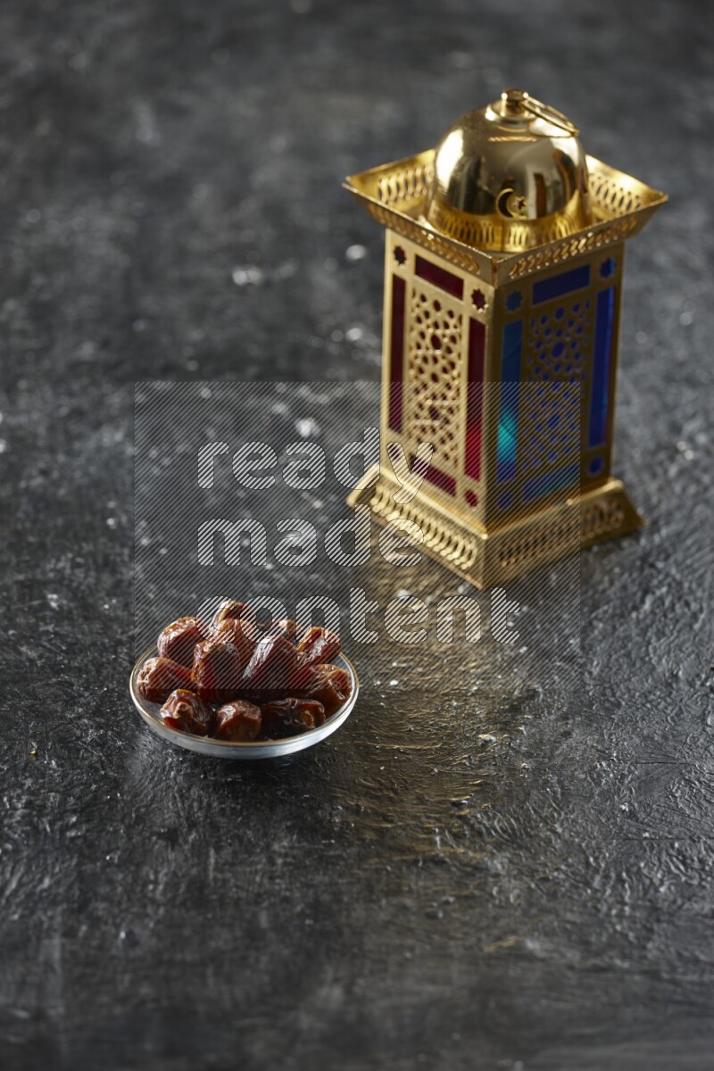 A golden lantern with different drinks, dates, nuts, prayer beads and quran on textured black background