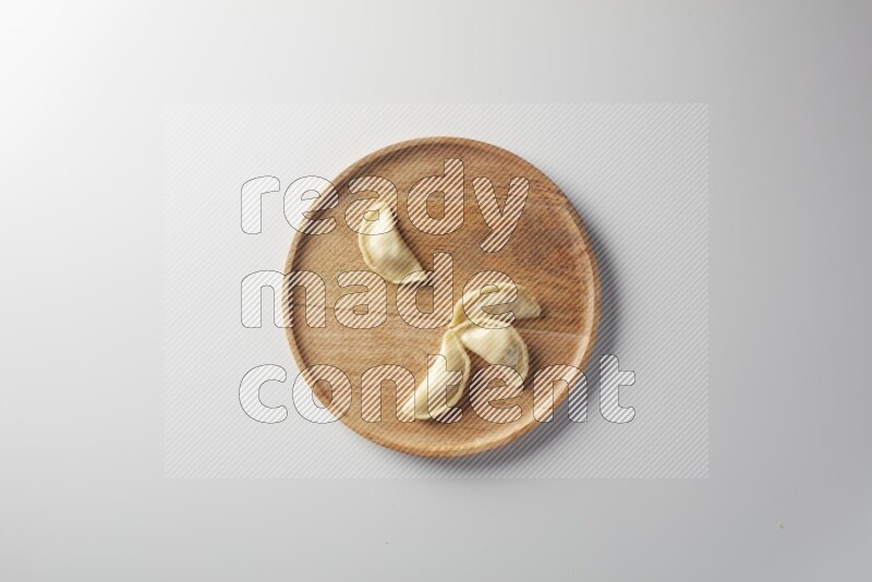 Four Sambosas on a wooden round plate on a white background