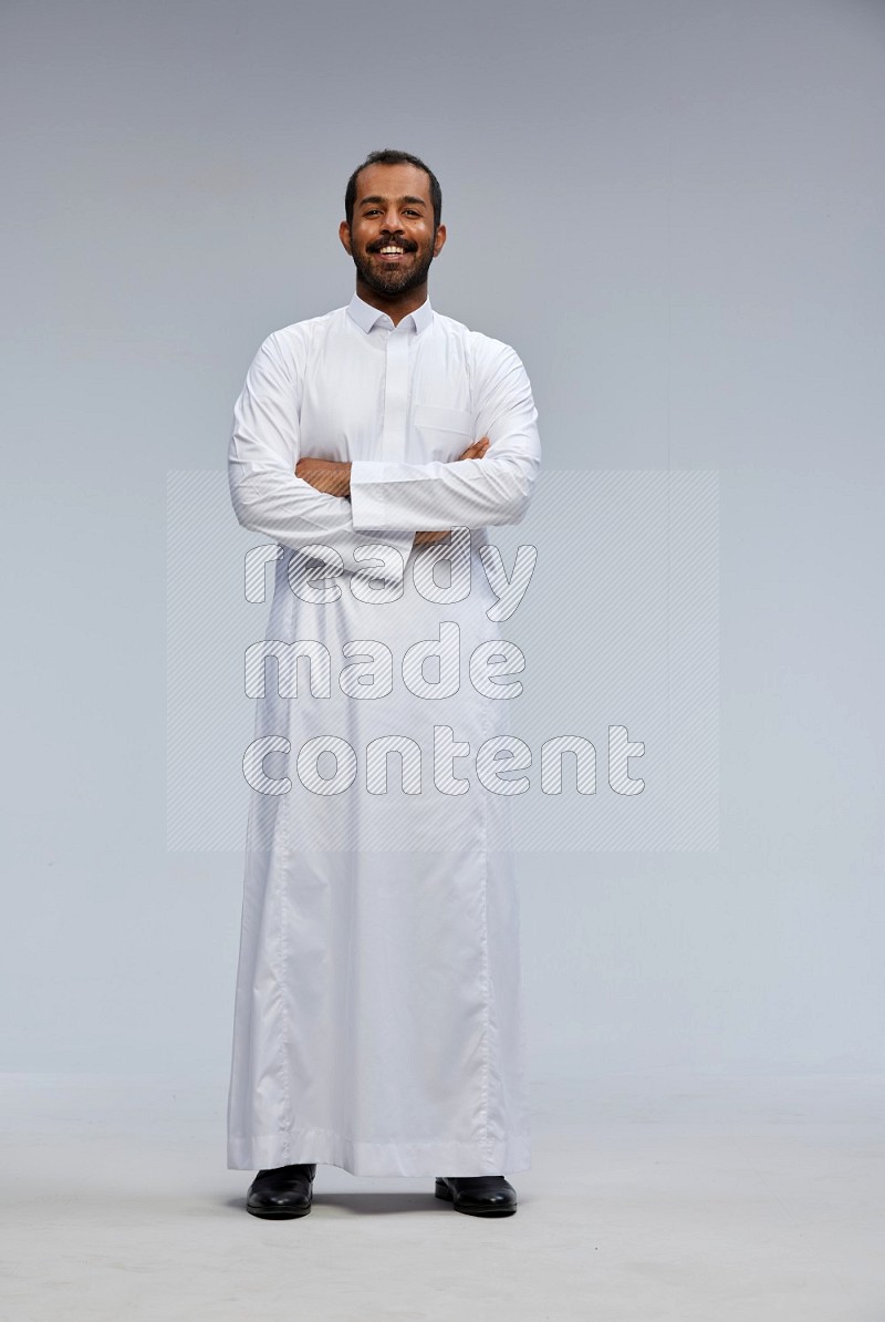 Saudi man wearing Thob standing with crossed arms on Gray background