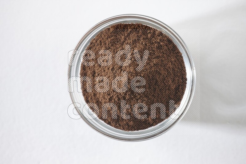 A glass bowl full of cloves powder on white flooring