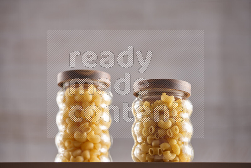 Raw pasta in glass jars on beige background
