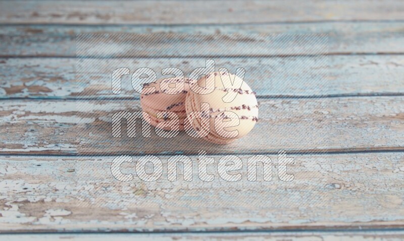 45º Shot of two pink orange blossom macarons on light blue wooden background