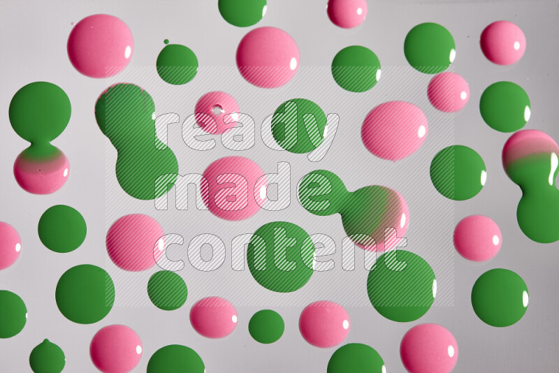 Close-ups of abstract pink and green paint droplets on the surface