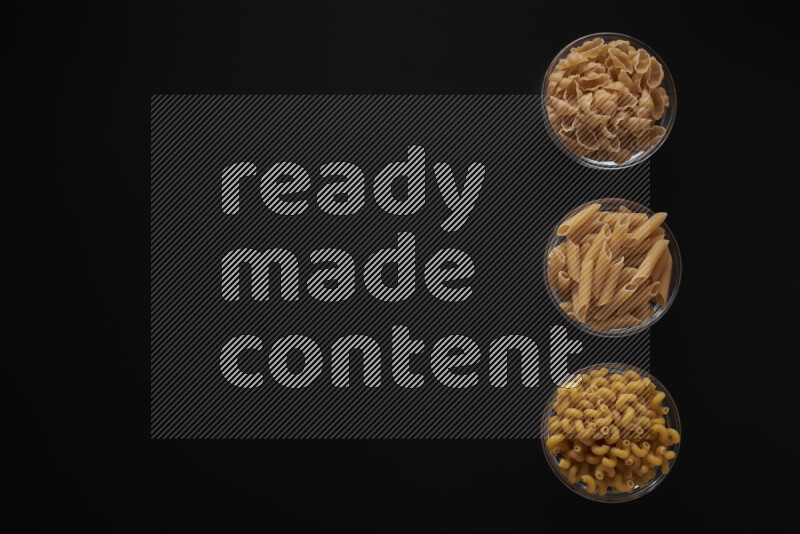 Different pasta types in 3 glass bowls on black background