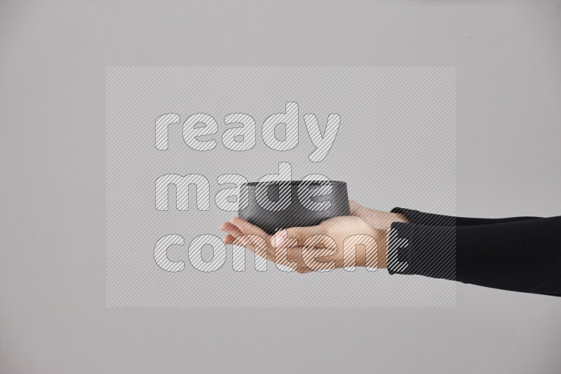 امرأة ترتدي عباءة سوداء تحمل أدوات فخارية مختلفة في أوضاع متعددة