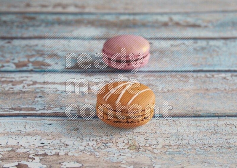 45º Shot of of two assorted Brown Irish Cream, and Purple Strawberry macarons  on light blue background