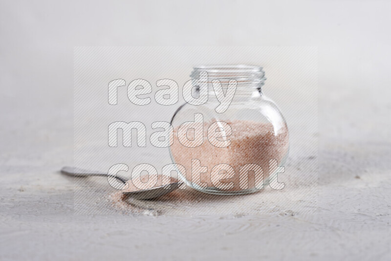 A glass jar full of fine himalayan salt on white background