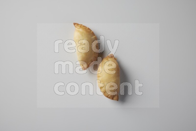 Two fried sambosa from a top angle on a white background