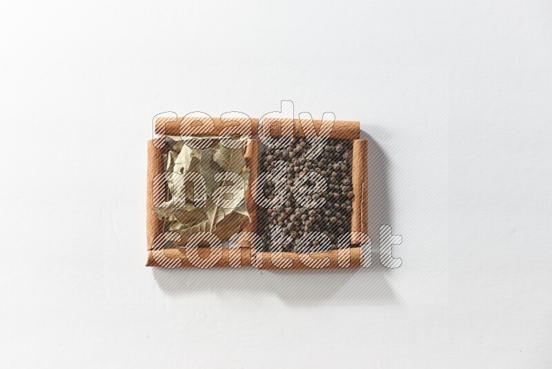 2 squares of cinnamon sticks full of black peppers and bay laurel leaves on white flooring