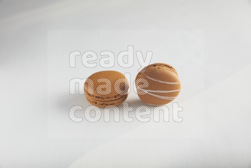 45º Shot of of two assorted Brown Irish Cream, and Brown Maple Taffy macarons  on white background